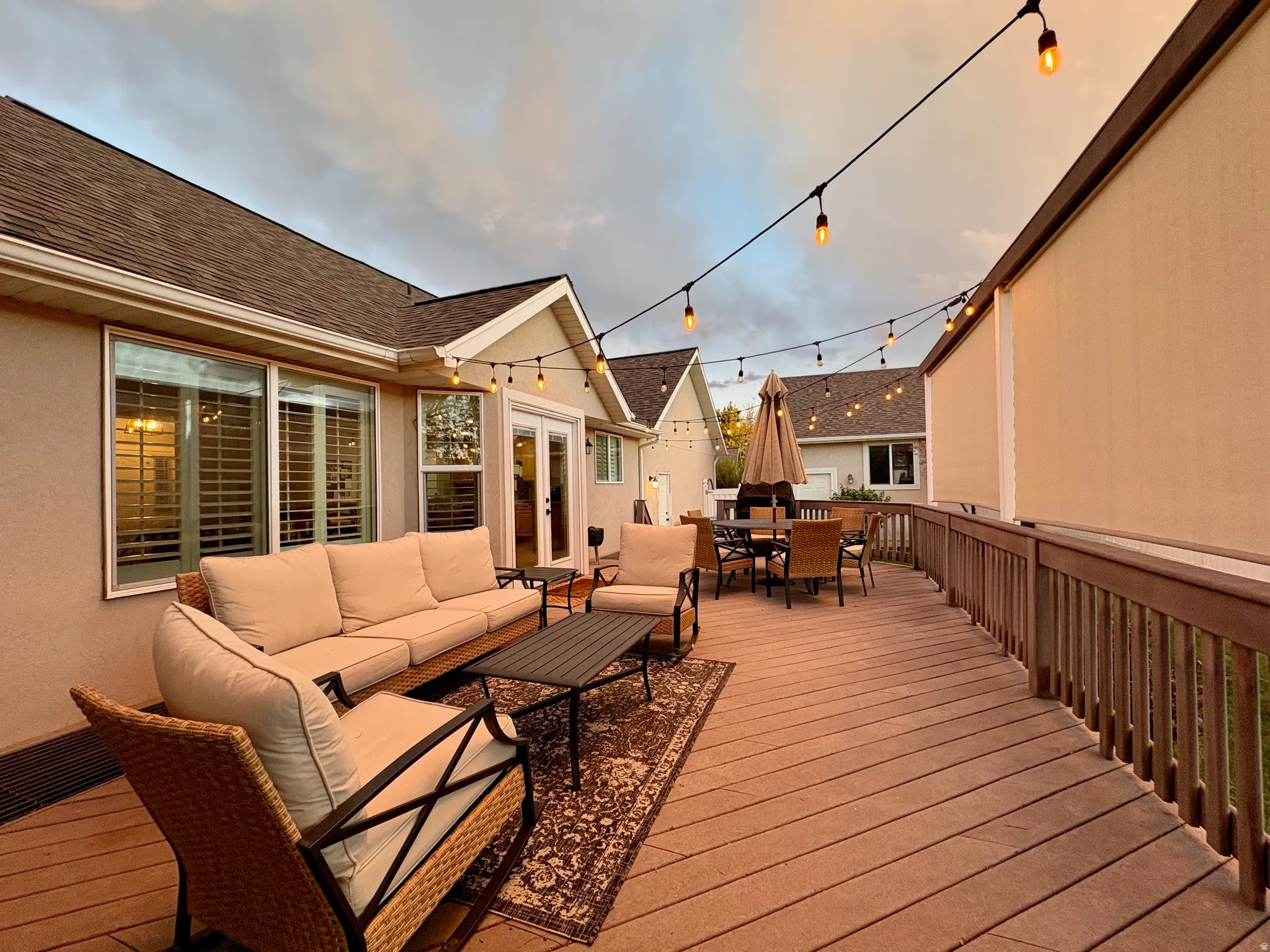 Spacious exterior deck with wood-finish flooring, protective railing, and exterior wall-mounted shades
