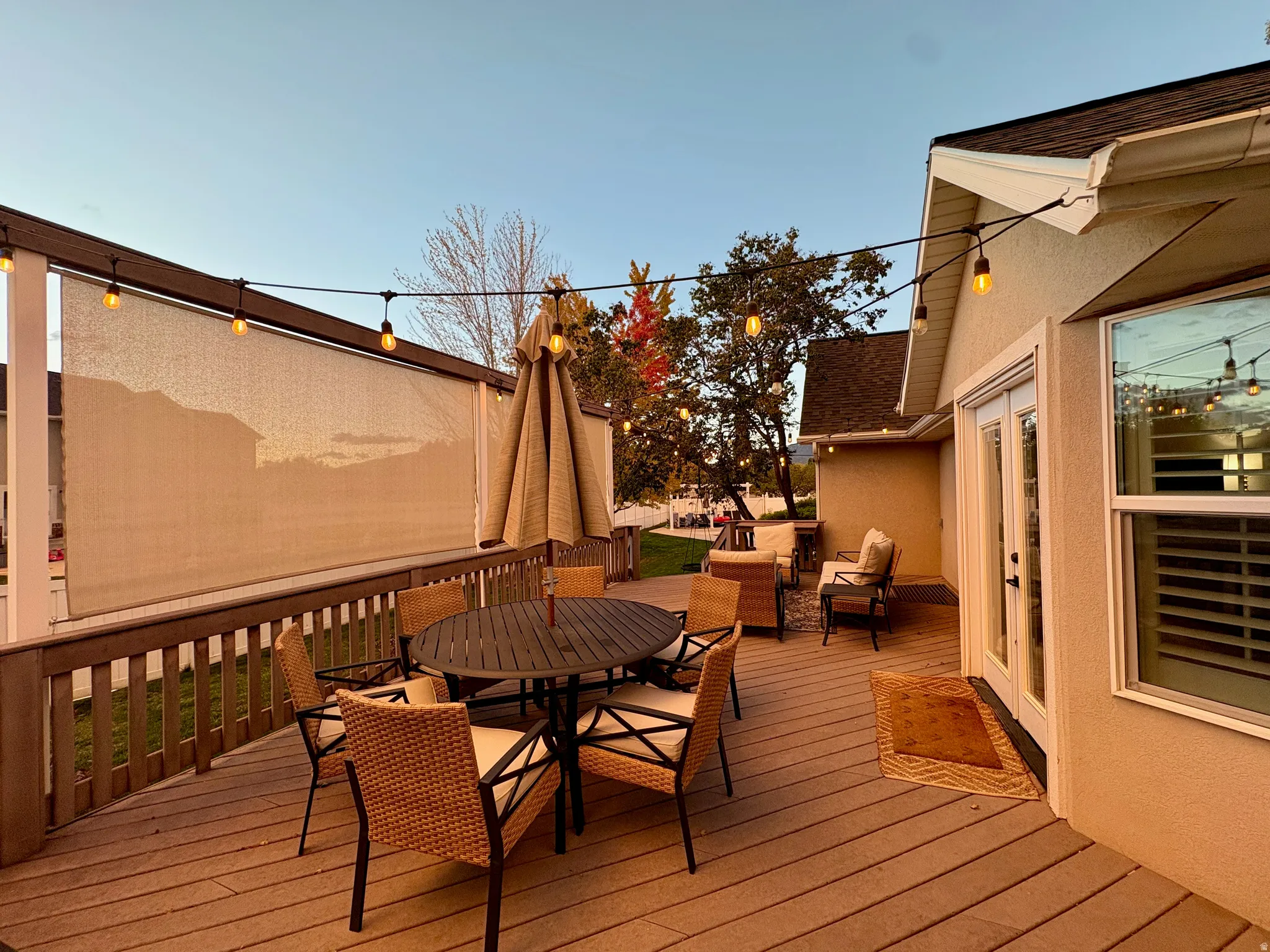 Expansive deck featuring composite decking, a privacy screen, string lighting, and direct access through a double glass door