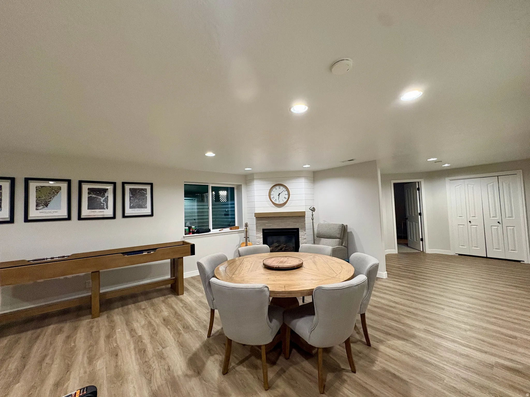Recessed lighting, wood-finish flooring, white walls, built-in fireplace with wood mantel, and a window with blinds