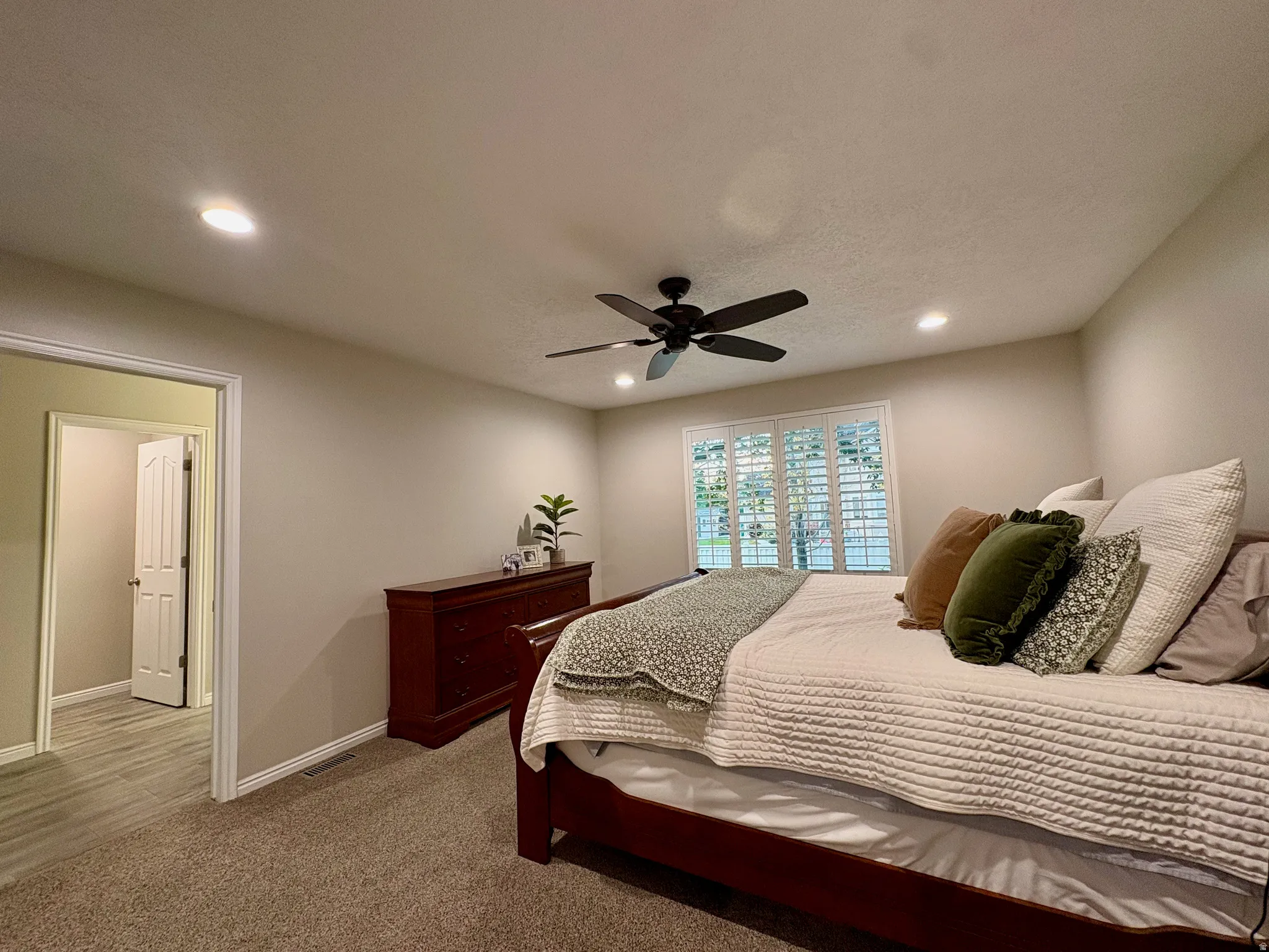 Recessed lighting, ceiling fan, window with plantation shutters, neutral wall color, and carpeted flooring