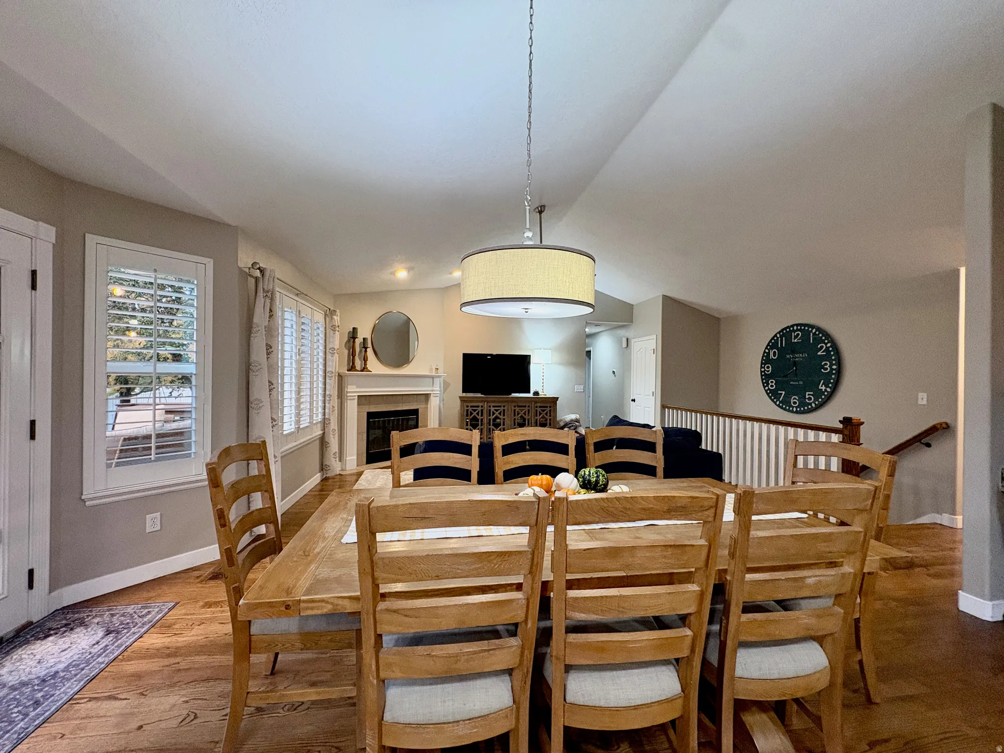 Hardwood flooring, white window shutters, fireplace with mantel, drum pendant light fixture, and white painted balusters