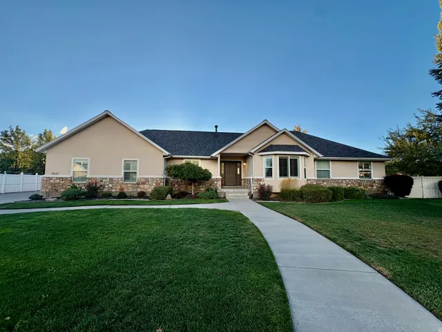 Stucco exterior with stone accenting, dark shingle roofing, and a bay window