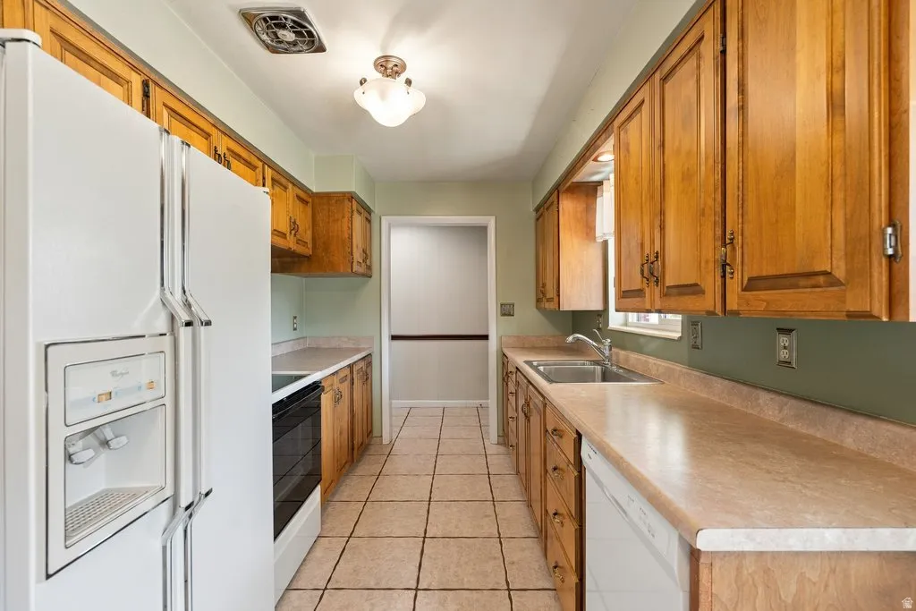 Galley kitchen featuring wood cabinetry, stone-look countertops, and tile flooring