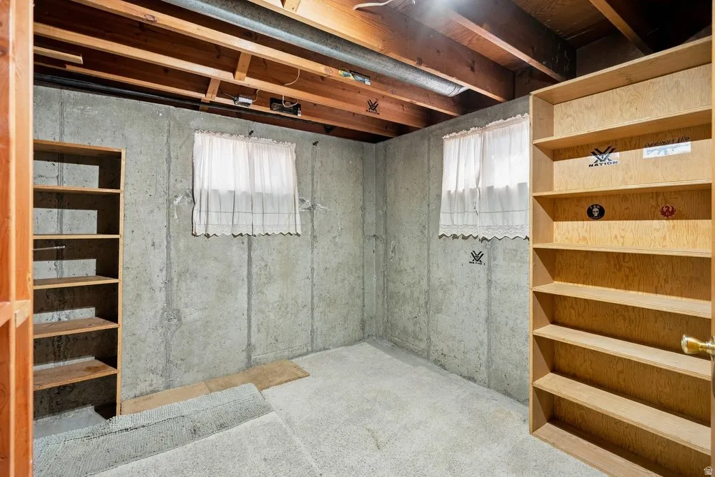 Exposed ceiling joists with concrete walls and light-colored flooring
