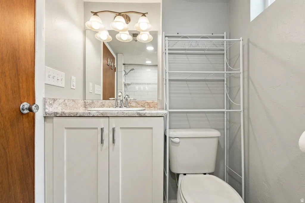 Vanity with a patterned countertop and undermount sink, overhead vanity lighting, and wall-mounted mirror