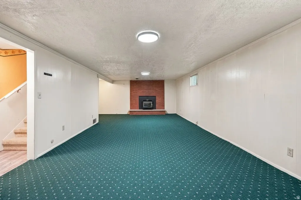 Spacious room featuring carpeting, a fireplace with a brick surround, and recessed lighting