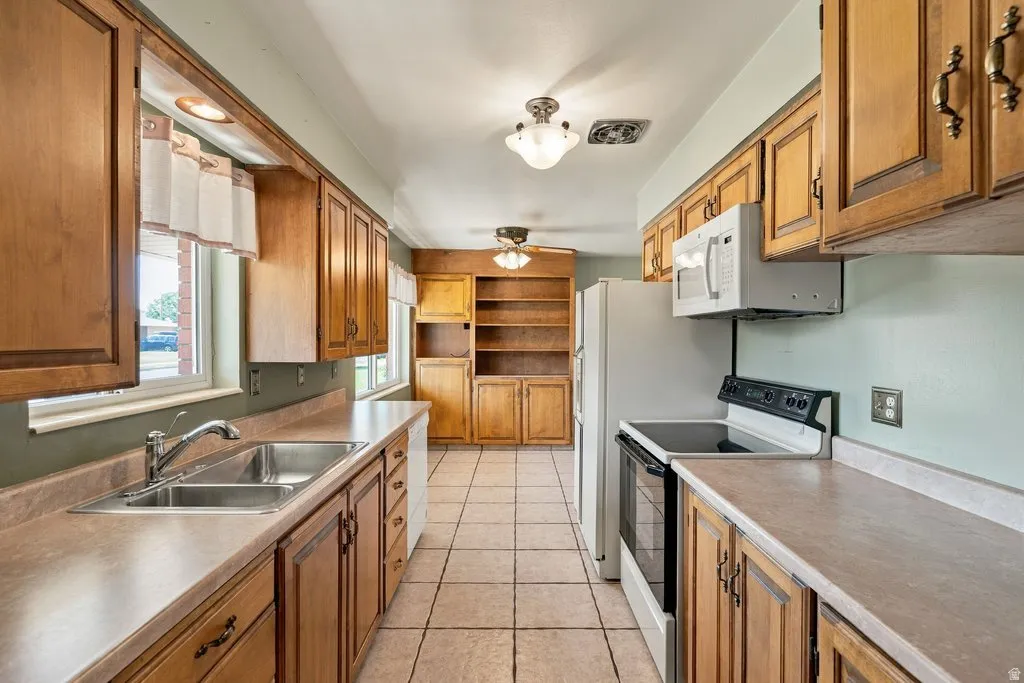 Kitchen with dual basin stainless steel sink, wood-finish cabinetry, tile flooring, and integrated built-in shelving