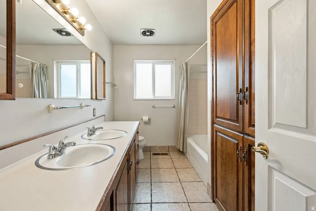 Dual vanity with integrated sinks, wood cabinetry, and a full-width mirror