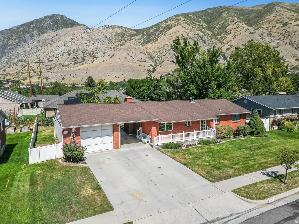 Red brick exterior with white trim, a covered porch, an attached garage, and a concrete driveway