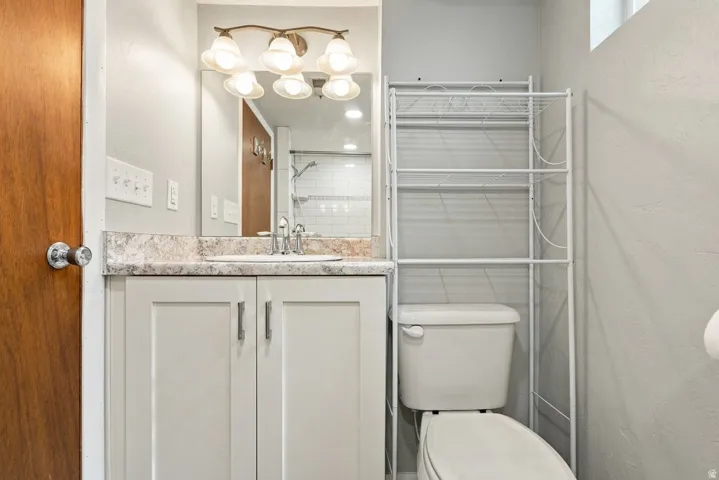 Vanity with a patterned countertop and undermount sink, overhead vanity lighting, and wall-mounted mirror
