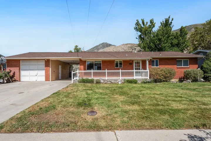 Brick exterior with a covered front porch, white railing, and a side-entry garage