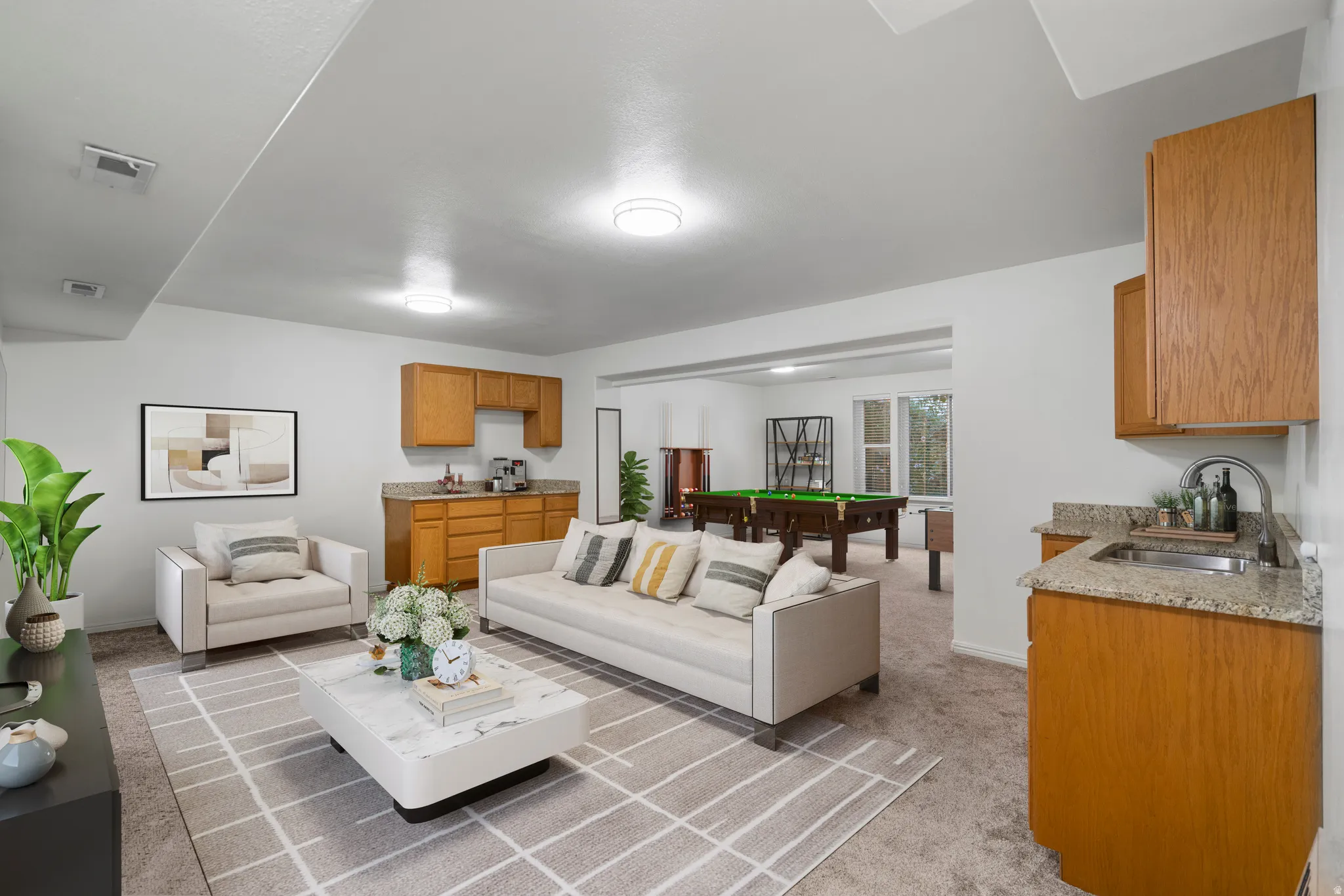 Open-concept living space with recessed lighting, two built-in wet bars featuring wood cabinetry and stone countertops, and carpeted flooring