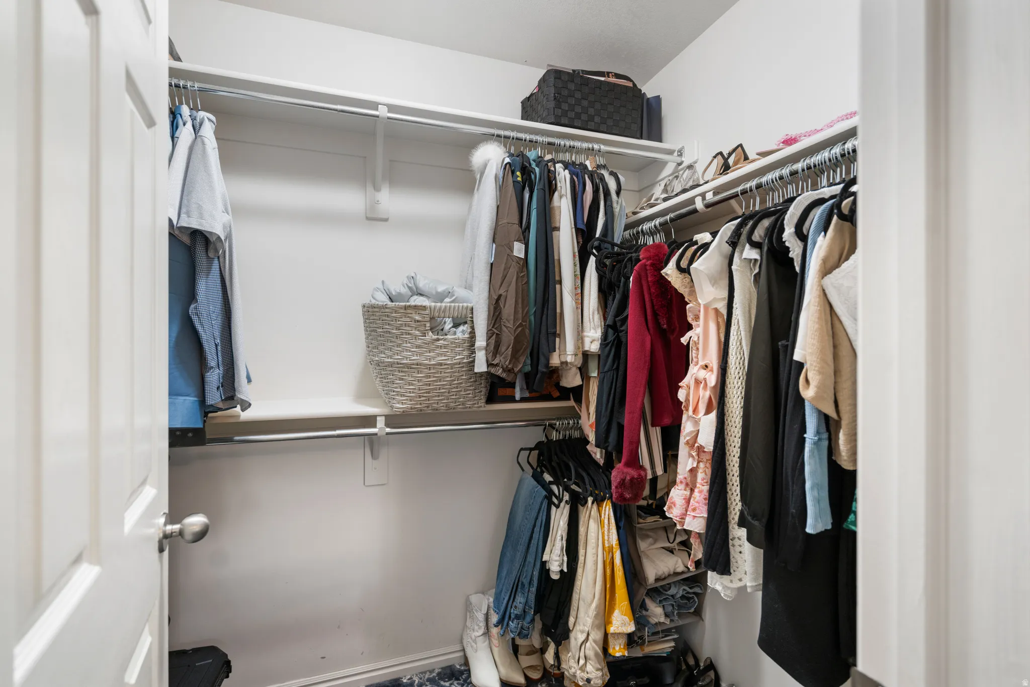 Primary Walk-in closet featuring white wire shelving, hanging rods, and a white paneled door