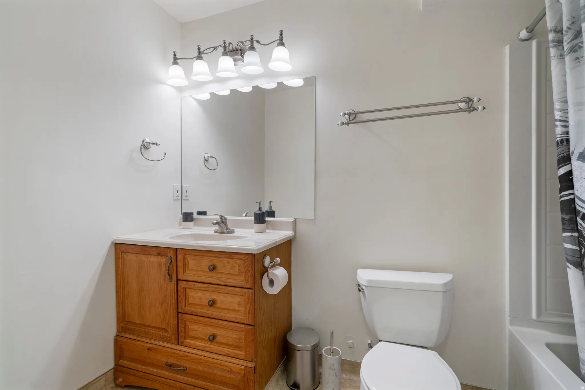 Wood-finish vanity with a single basin sink, white countertop, and integrated storage