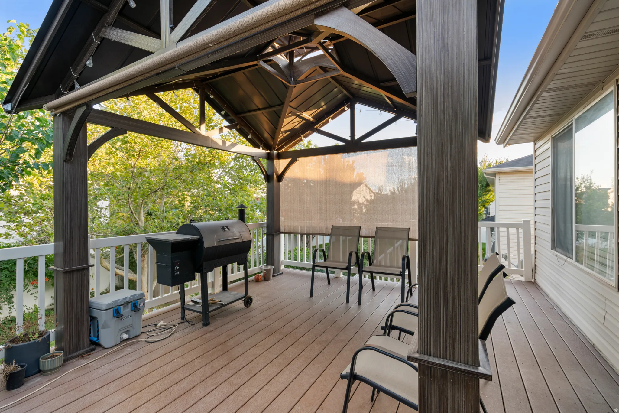 Expansive deck featuring a covered gazebo with string lighting, composite decking, and a privacy screen