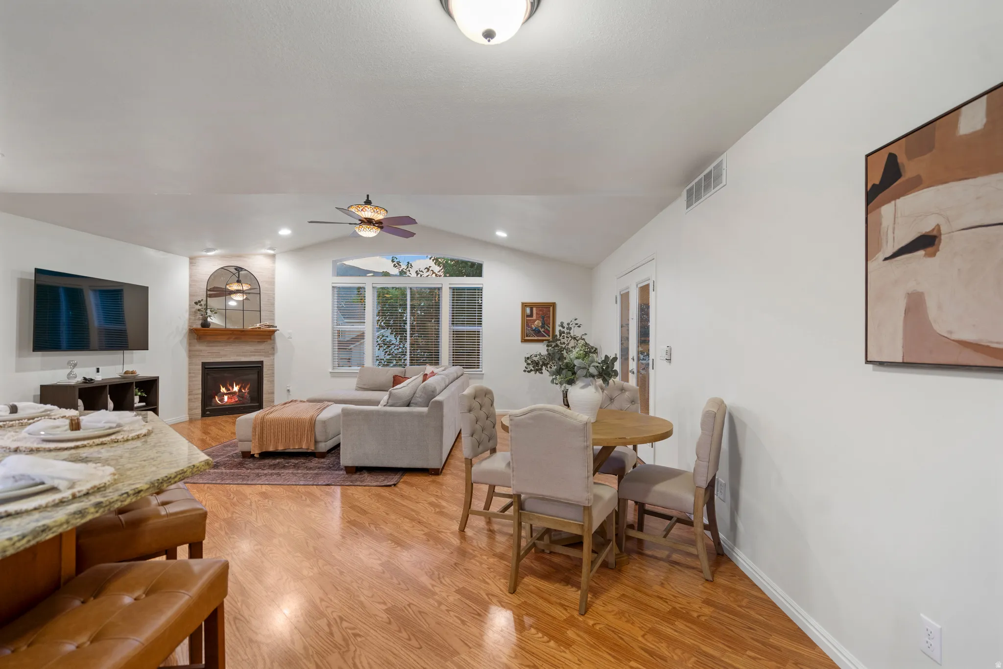 Vaulted ceilings, wood-finish flooring, and a fireplace with a stone surround
