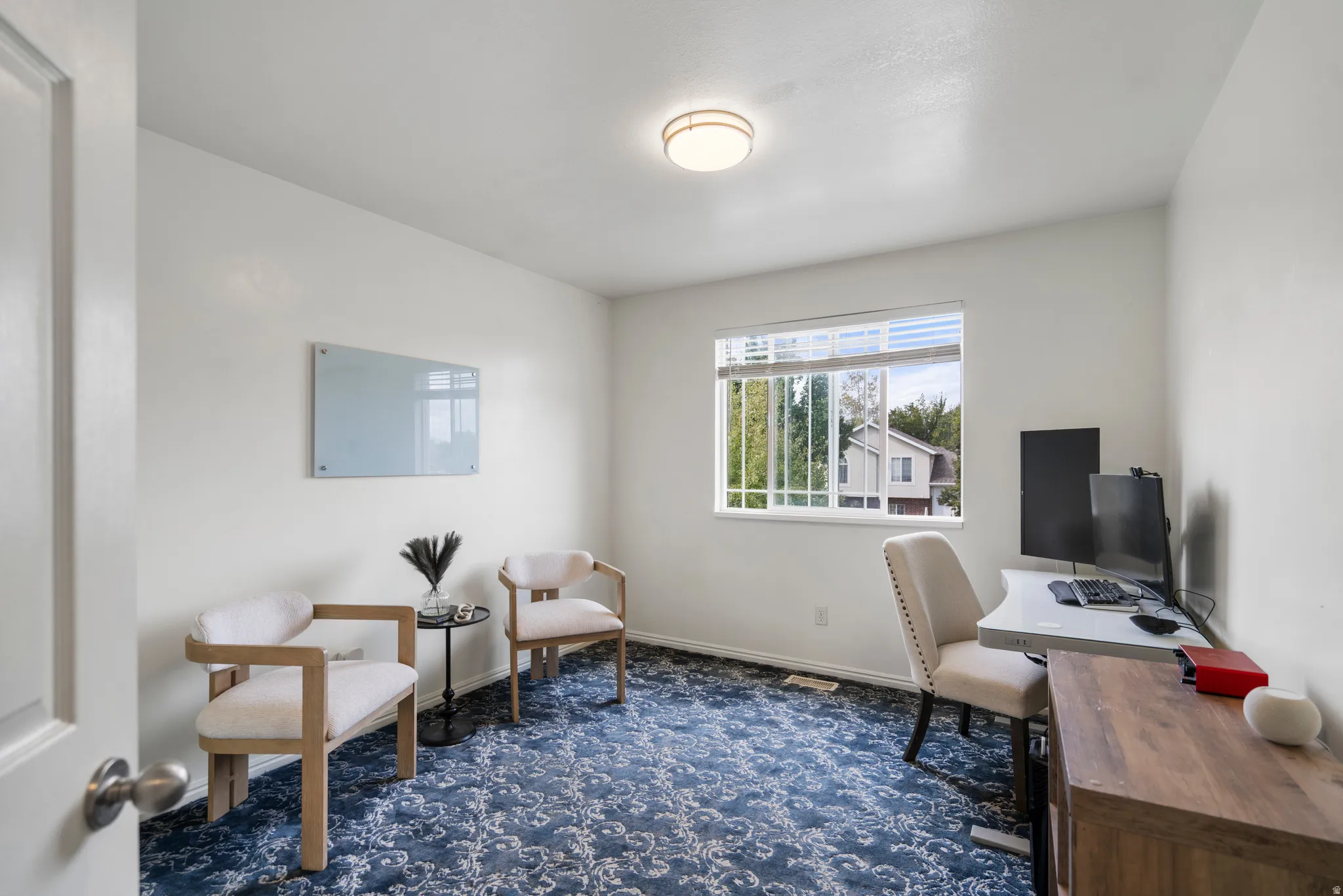 Window with blinds, wall-to-wall patterned carpet, and ceiling-mounted light fixture