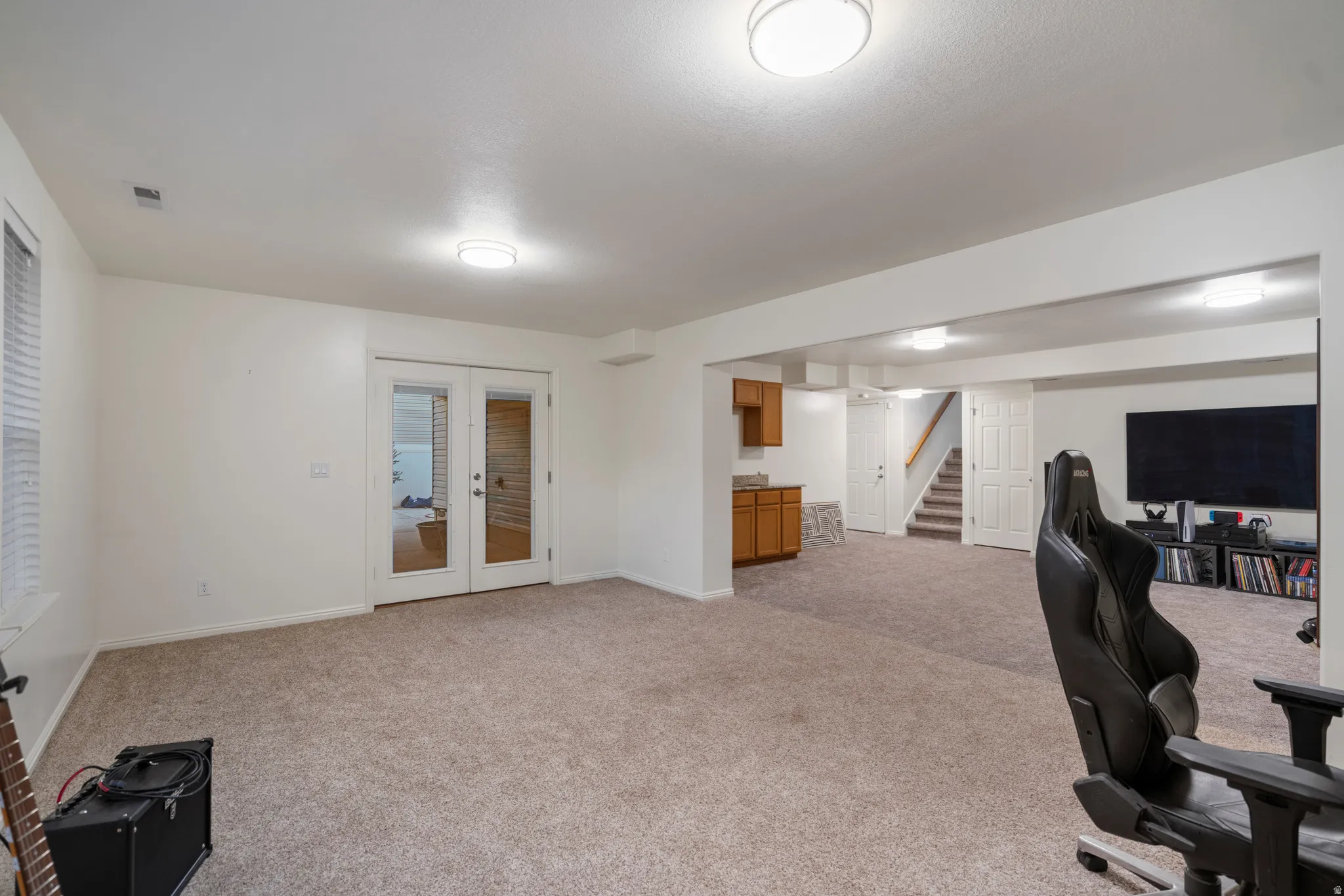 Carpeted flooring throughout, recessed ceiling lighting, a window with blinds, and French doors