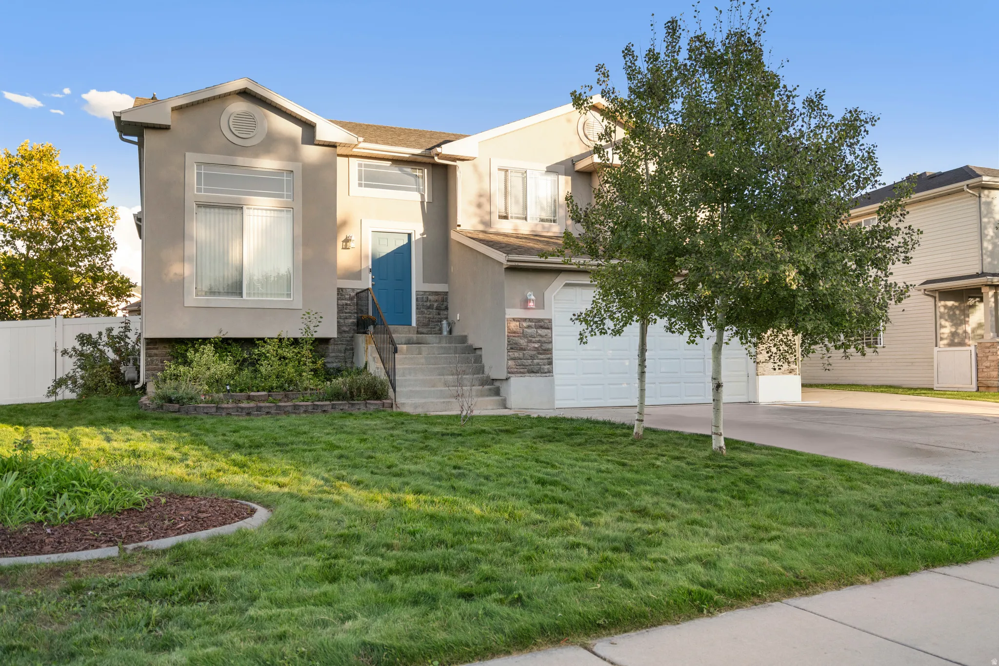 Stucco exterior with stone accents, a two-car garage, and a concrete driveway