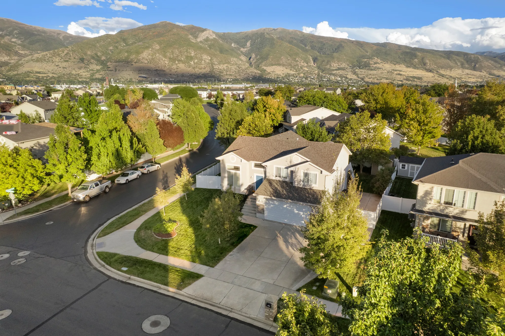 Two-story residential architecture with an attached two-car garage, concrete driveway, and established landscaping