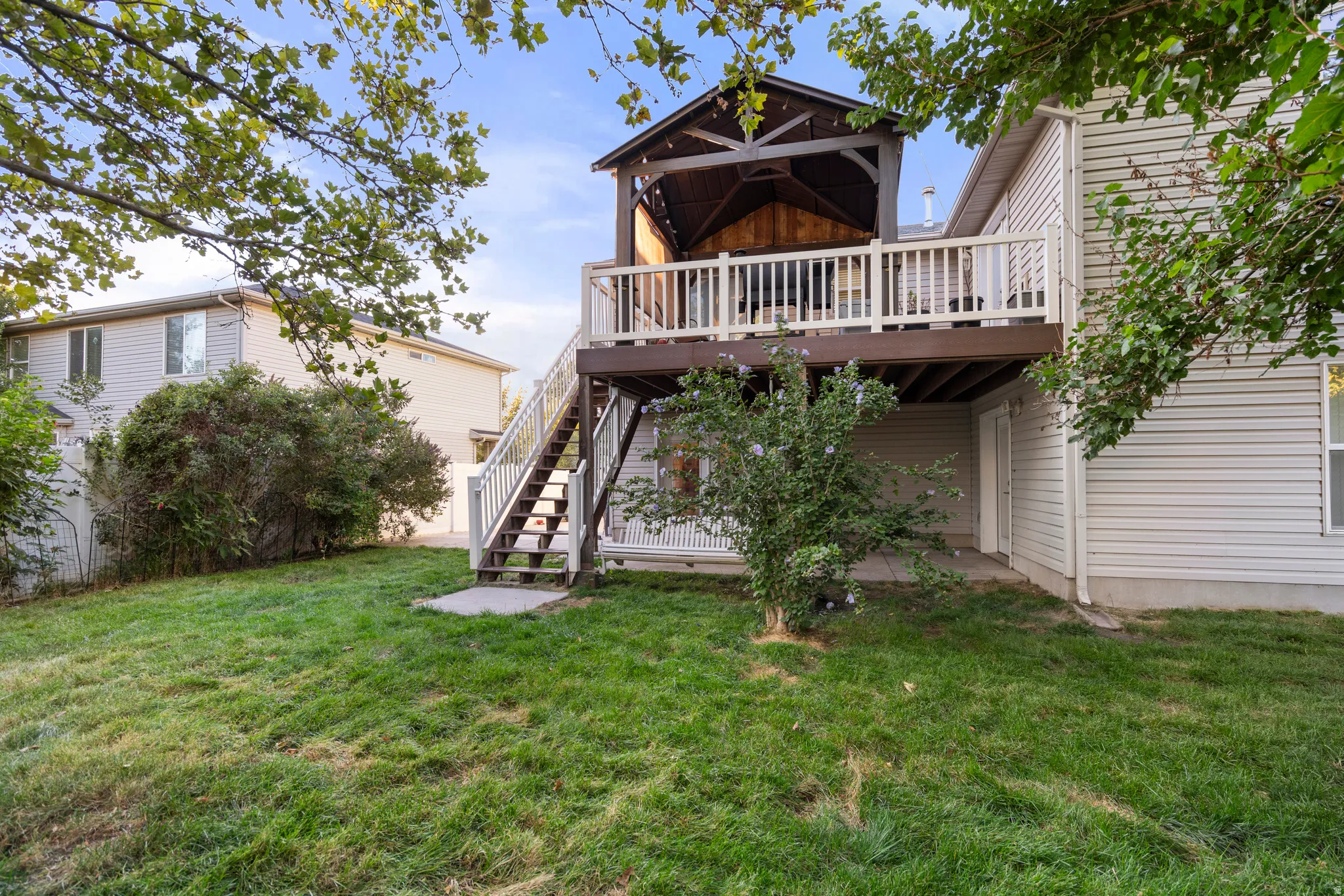 Elevated deck with white railings and dark wood flooring, leading to a covered pergola