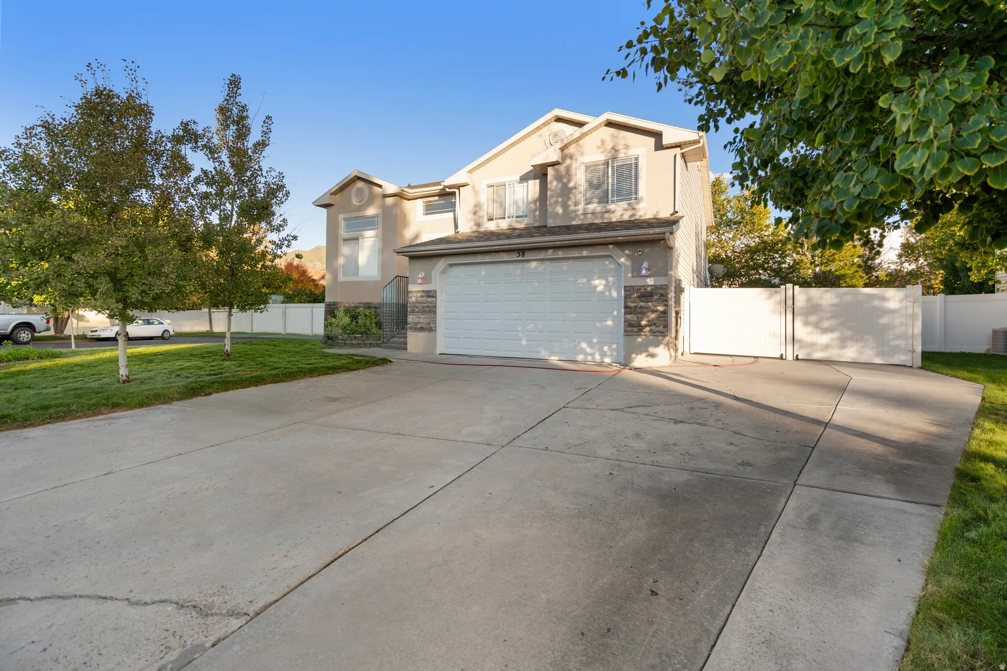 Two-story stucco exterior with stone accents, a two-car garage, and a concrete driveway