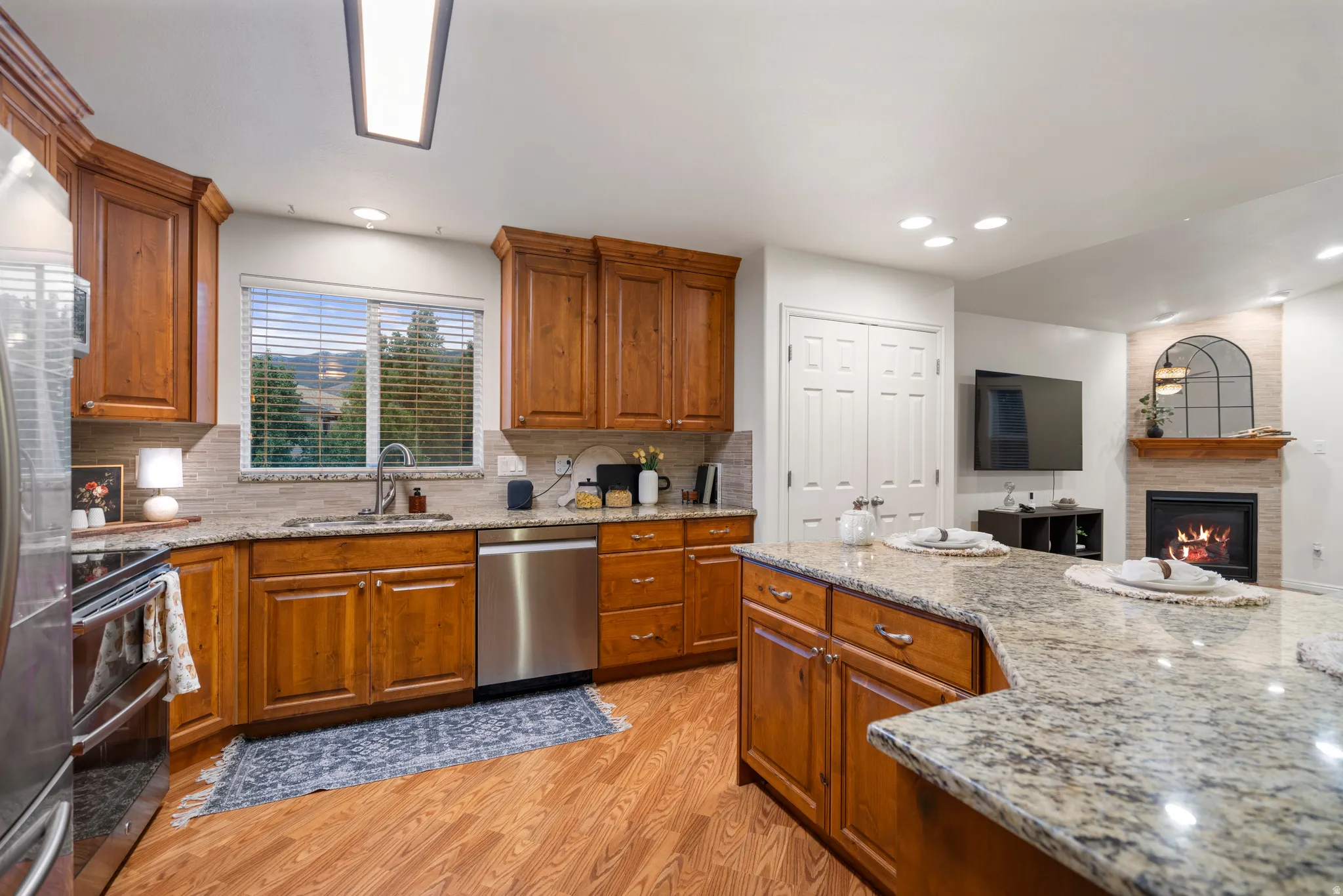 Kitchen featuring wood-finish flooring, wood cabinetry, stone countertops, and stainless steel appliances