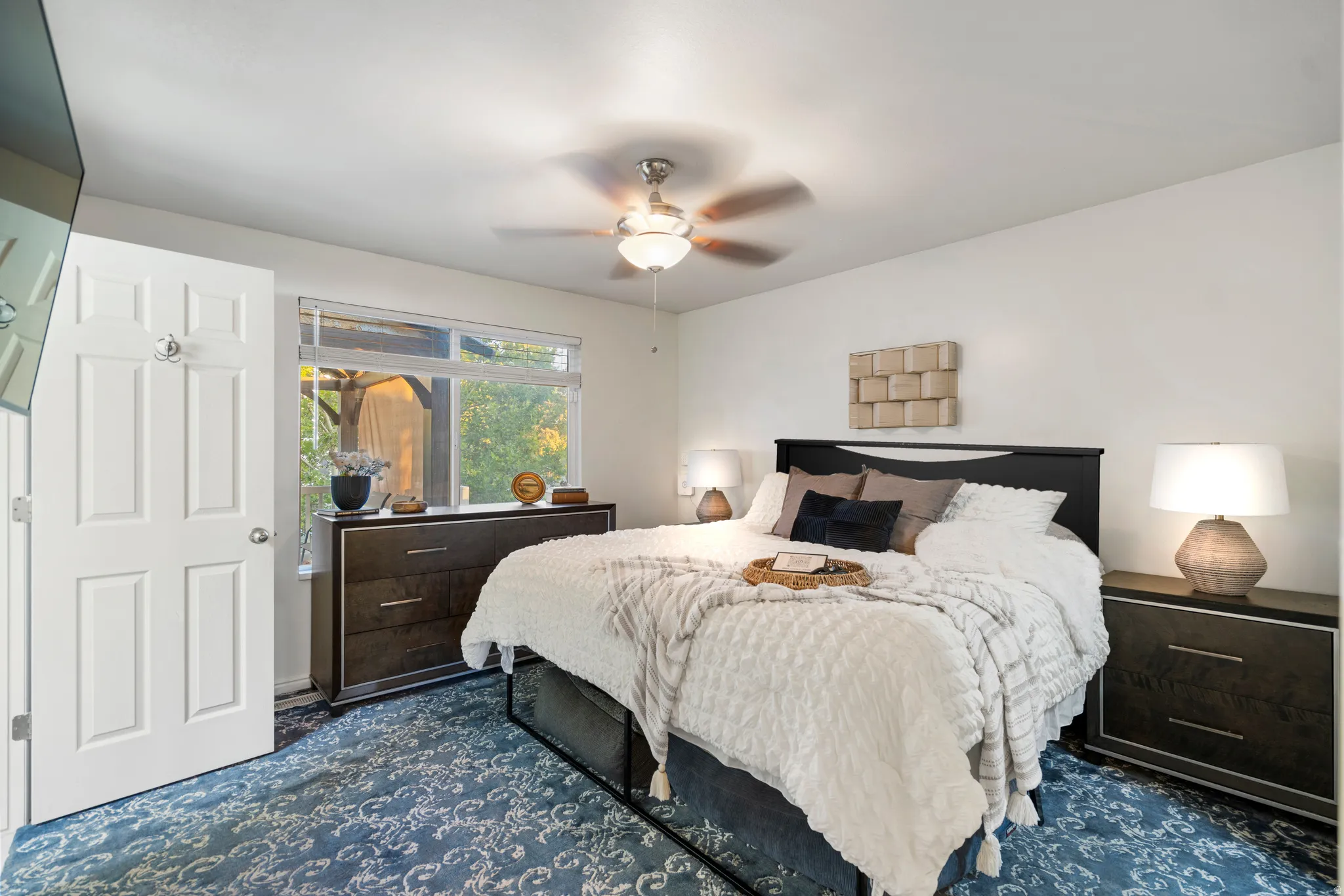 White paneled door, window with natural surroundings, ceiling fan with light fixture, and dark wood-finish furniture