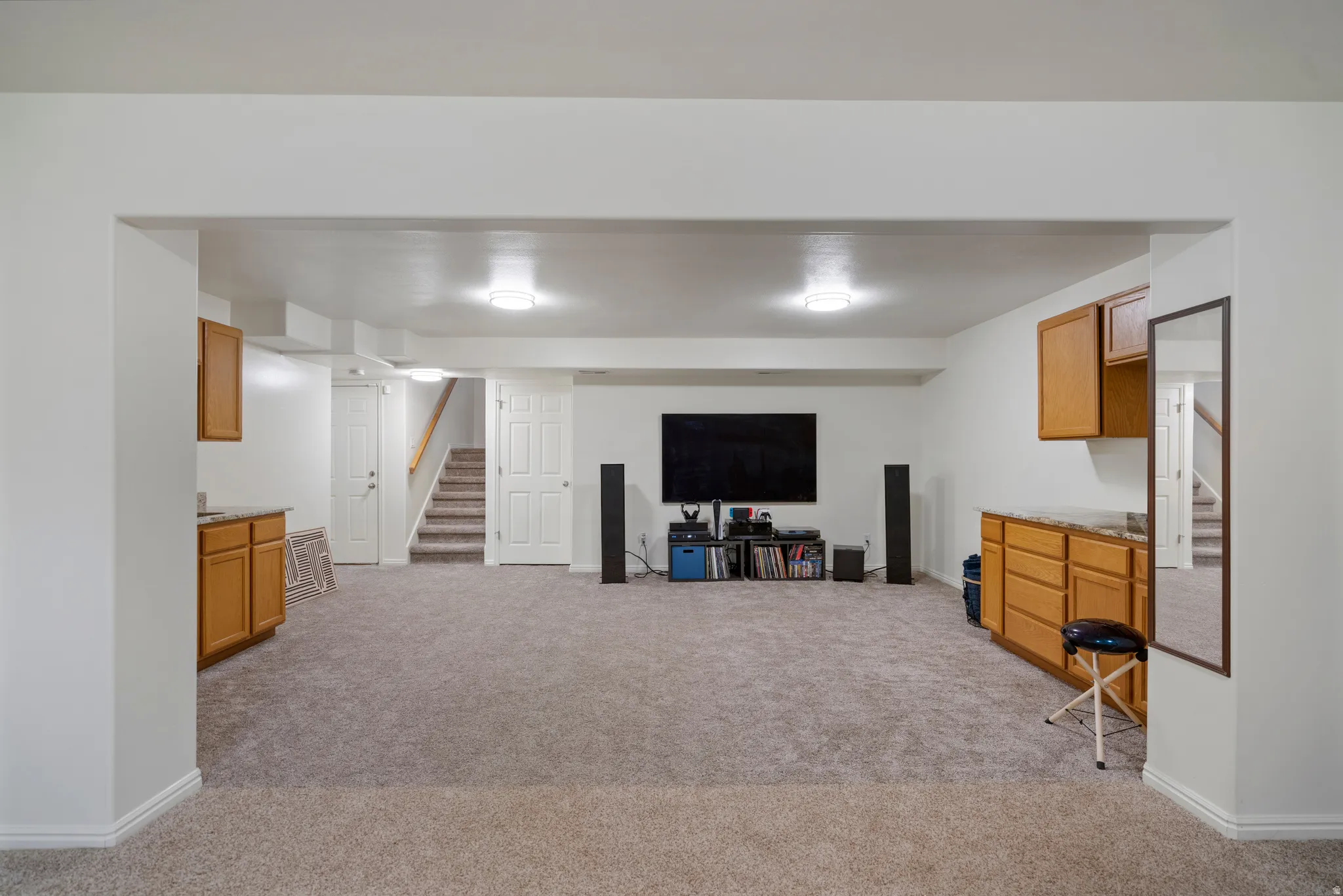 Spacious carpeted area with recessed lighting, built-in cabinetry, and a light-toned staircase