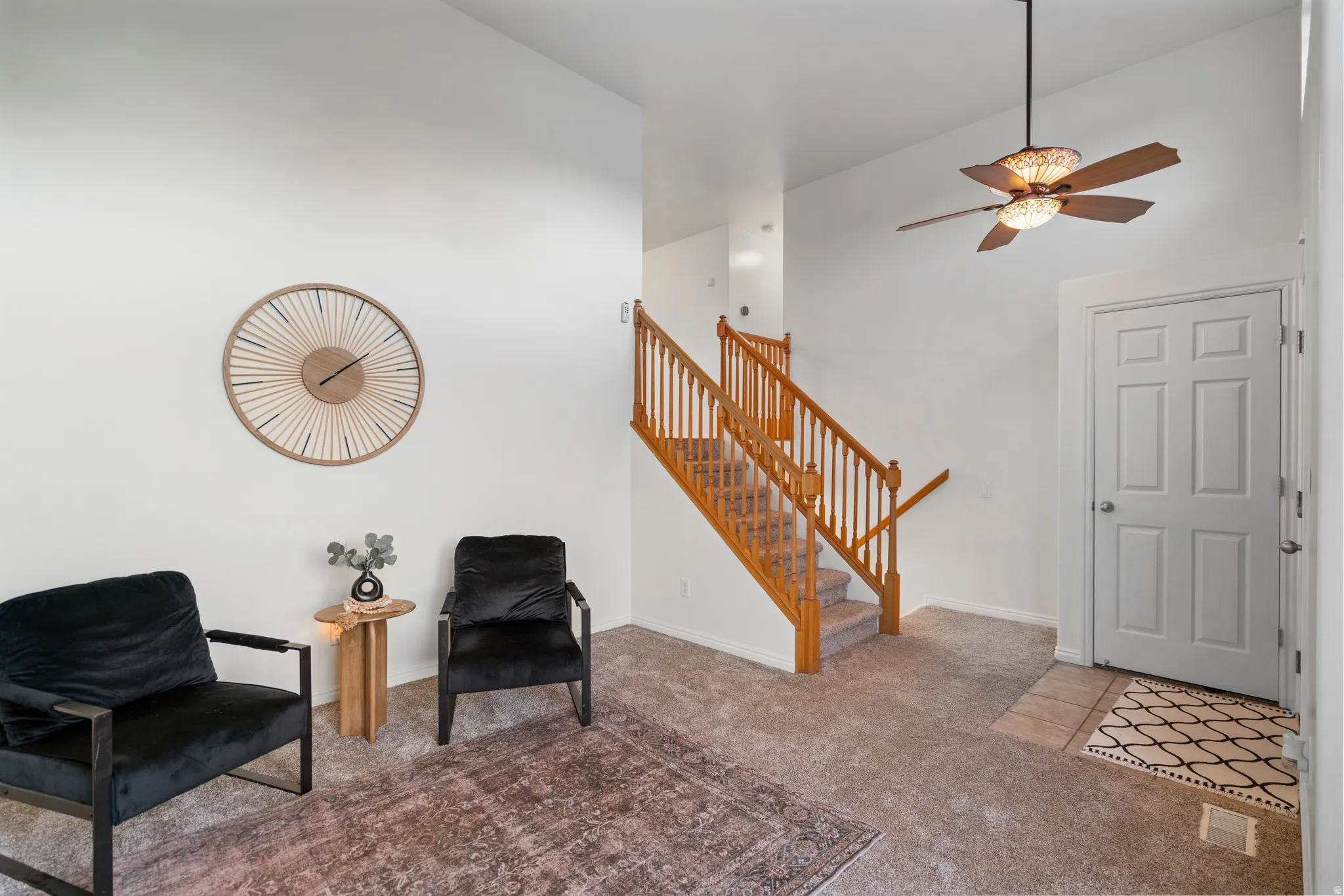 Vaulted ceiling, ceiling fan with integrated lighting, wood staircase with balusters, paneled interior door, and neutral carpeting