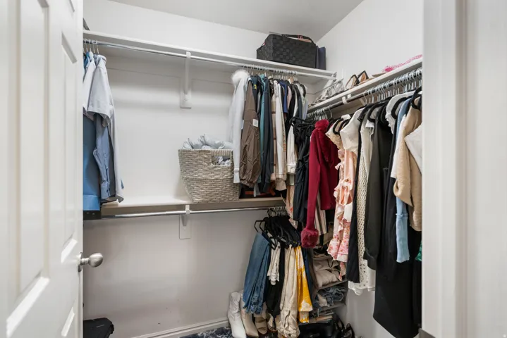 Primary Walk-in closet featuring white wire shelving, hanging rods, and a white paneled door