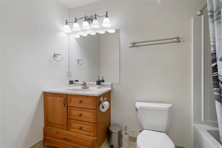 Wood-finish vanity with a single basin sink, white countertop, and integrated storage