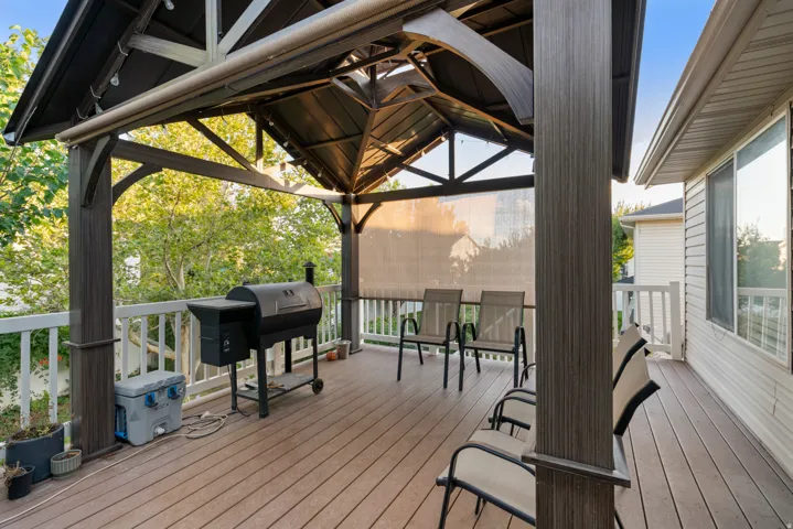Expansive deck featuring a covered gazebo with string lighting, composite decking, and a privacy screen