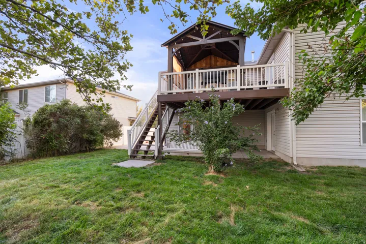 Elevated deck with white railings and dark wood flooring, leading to a covered pergola