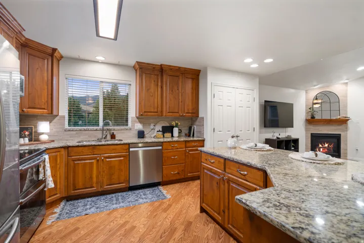 Kitchen featuring wood-finish flooring, wood cabinetry, stone countertops, and stainless steel appliances