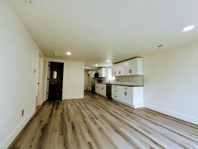 Modern kitchen area featuring white cabinetry, dark countertops, and a white subway tile backsplash