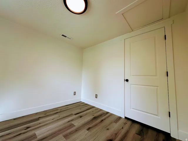 Wood-finish flooring, white walls, and a contemporary flush-mount ceiling light