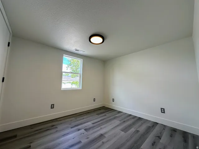 Recessed overhead lighting, a single window, and wood-finish flooring