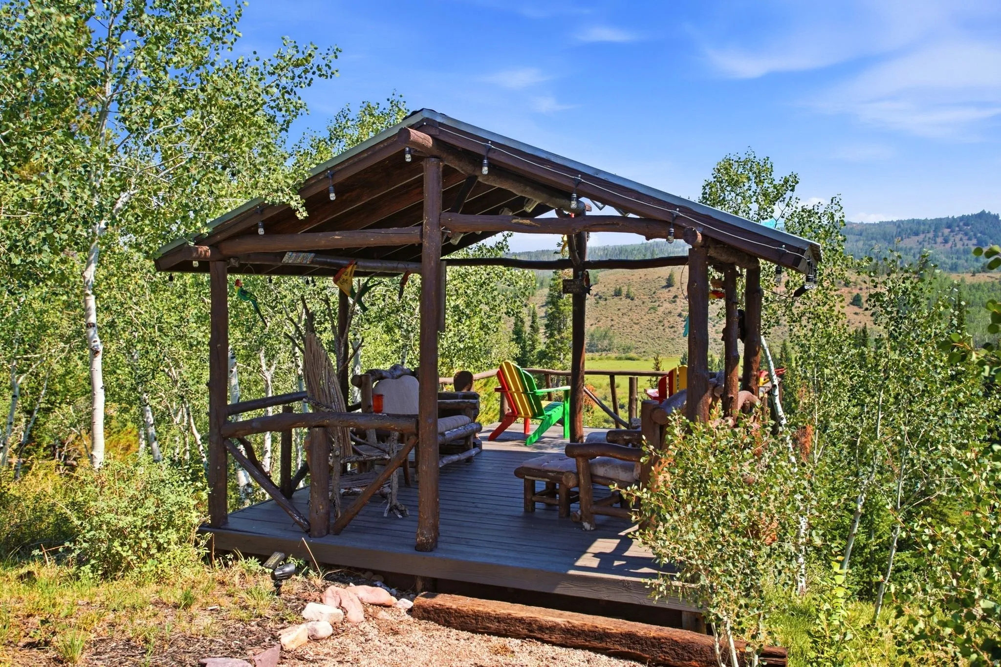 Wood-frame gazebo with a composite deck, surrounded by mature trees, offering an elevated position