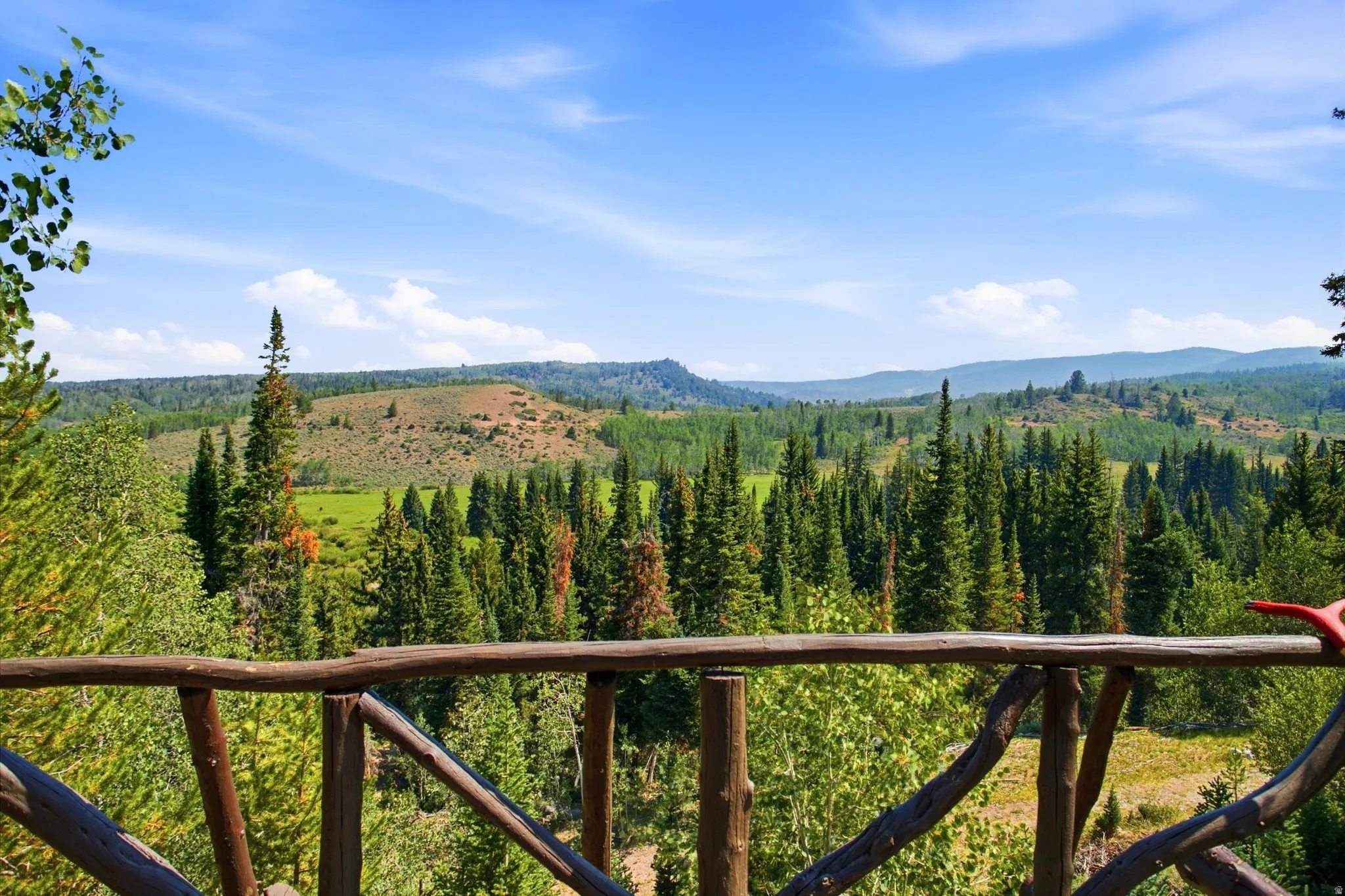 Wood-finish railing overlooking expansive forested landscapes