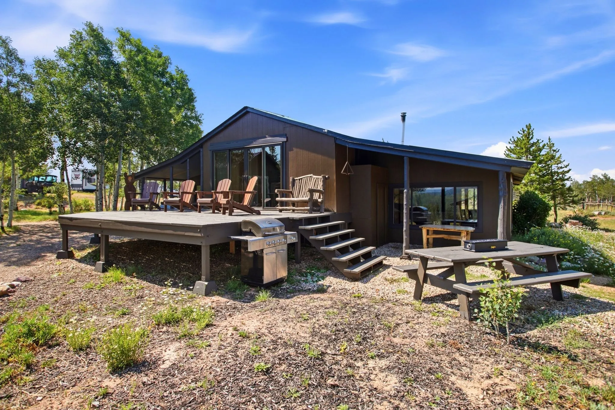 Brown exterior featuring a dark-toned elevated deck, sliding glass doors, and a covered porch