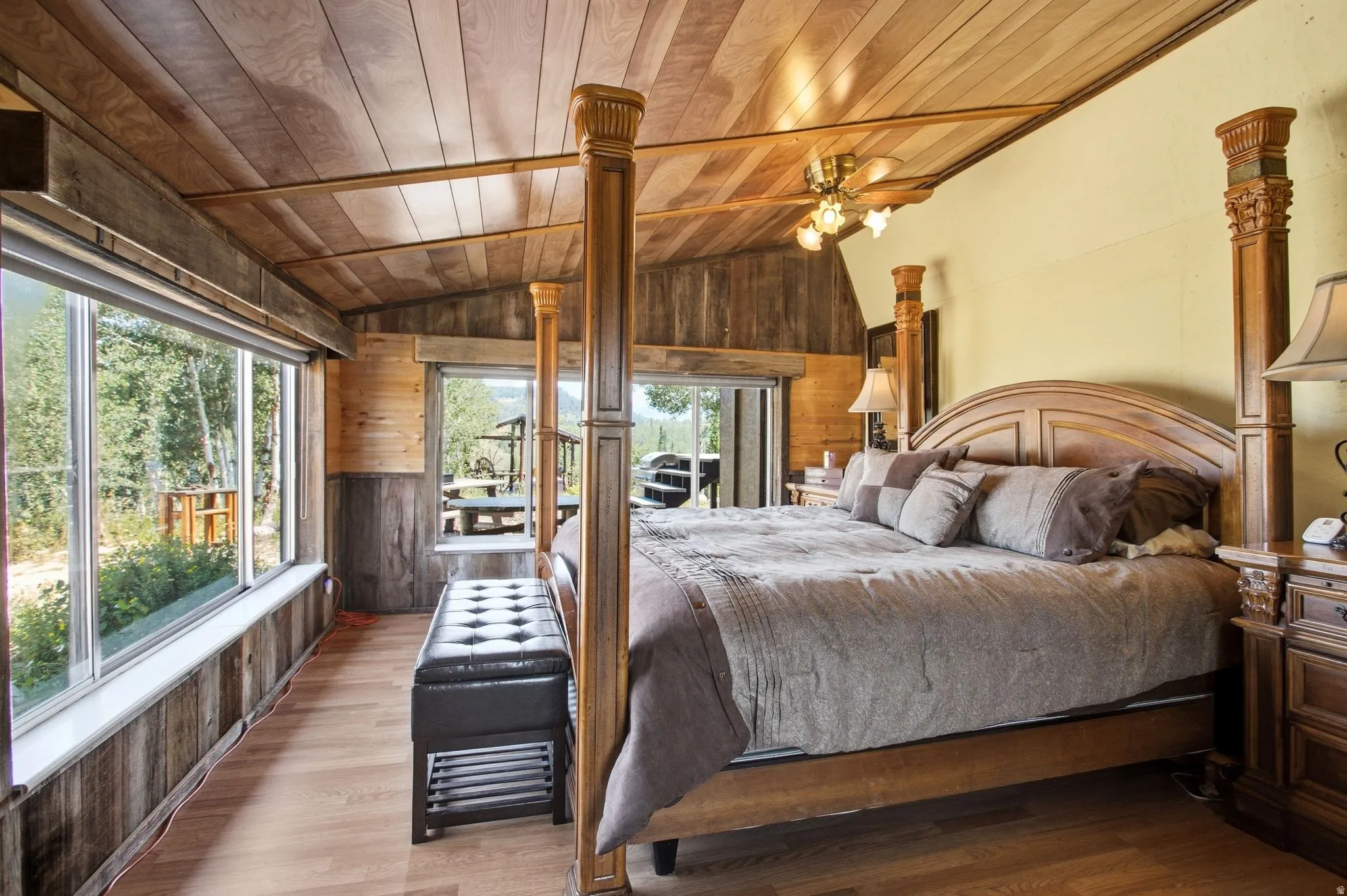 Wood-finish flooring with extensive wall paneling, a slatted wood-paneled ceiling, and large picture windows