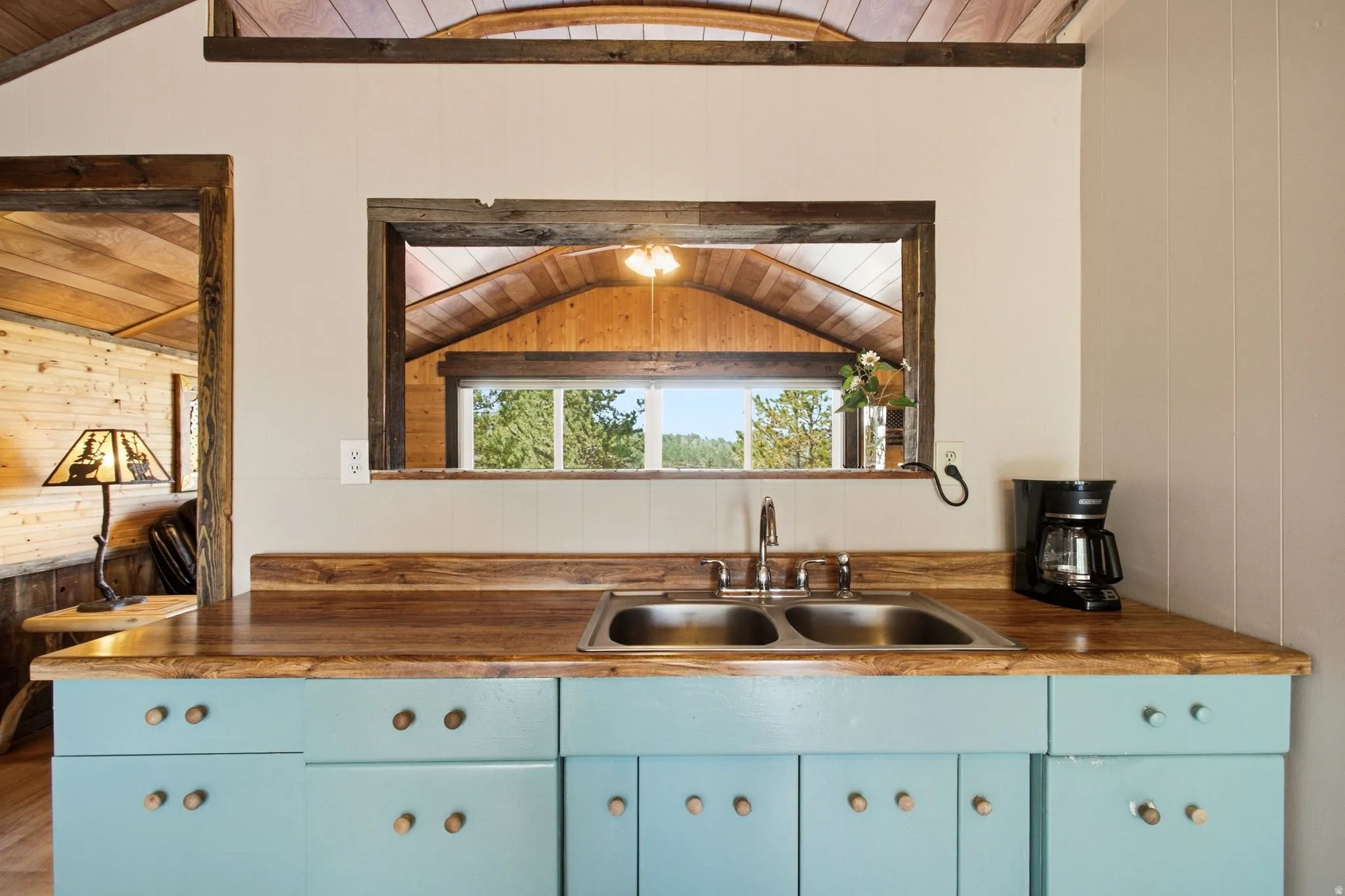 Wood-finish countertops, dual stainless steel sinks, and light blue cabinetry