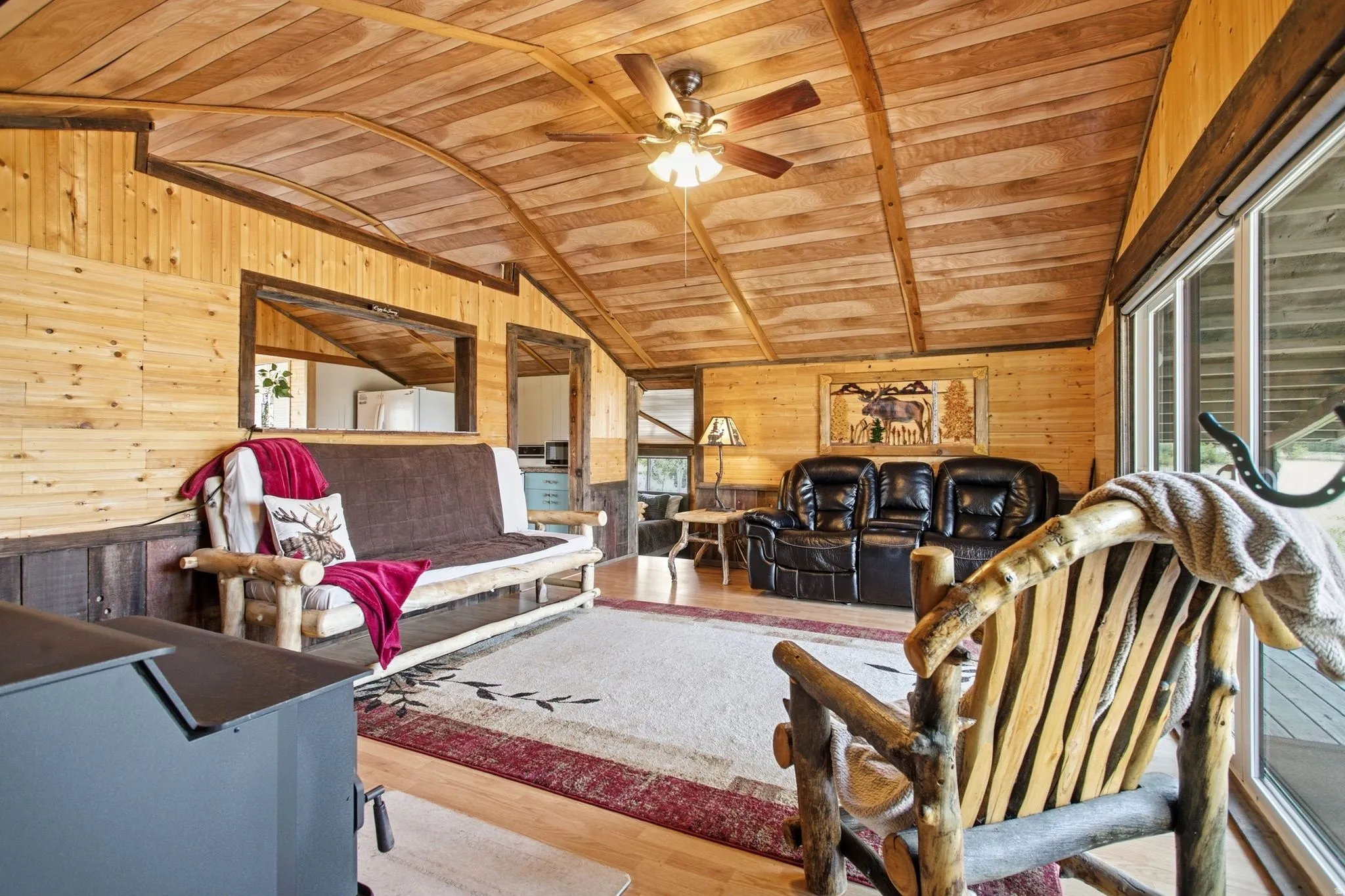 Vaulted wood-paneled ceiling with ceiling fan, wood-paneled walls, and sliding glass door