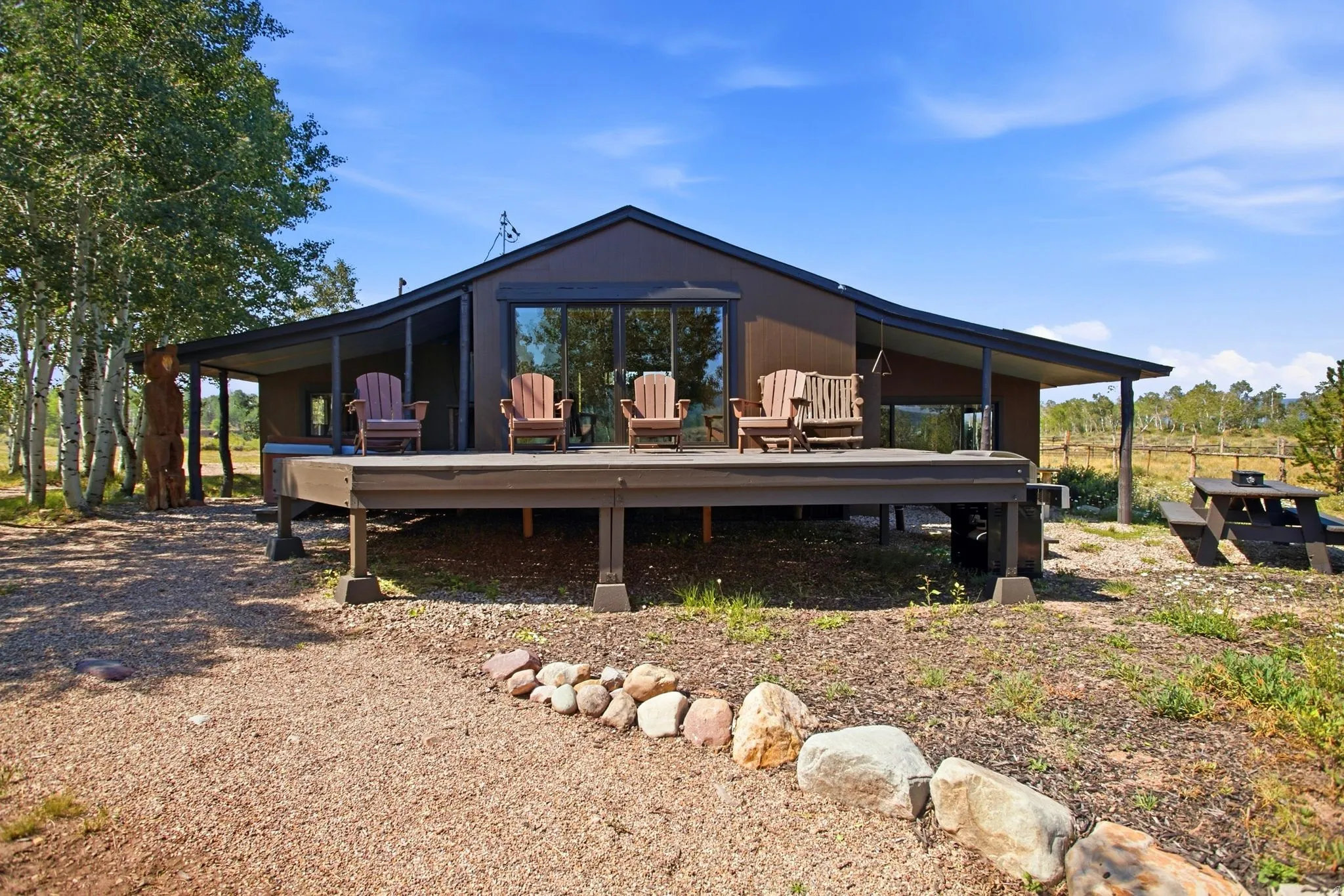 Raised deck with covered porch, sliding glass doors, and gravel landscaping