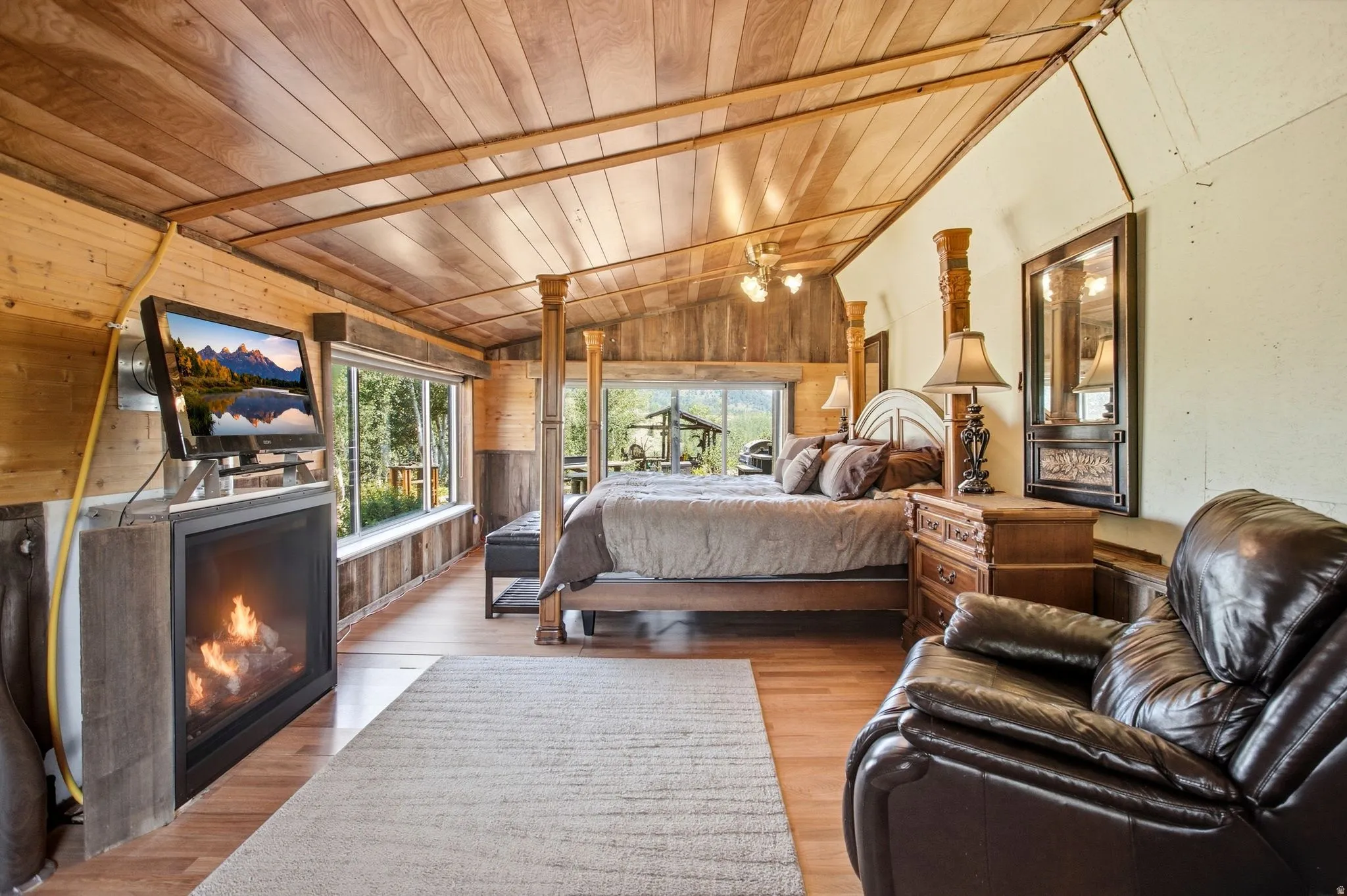 Wood-paneled vaulted ceiling with exposed beams, wood-finish flooring, built-in fireplace, and expansive windows