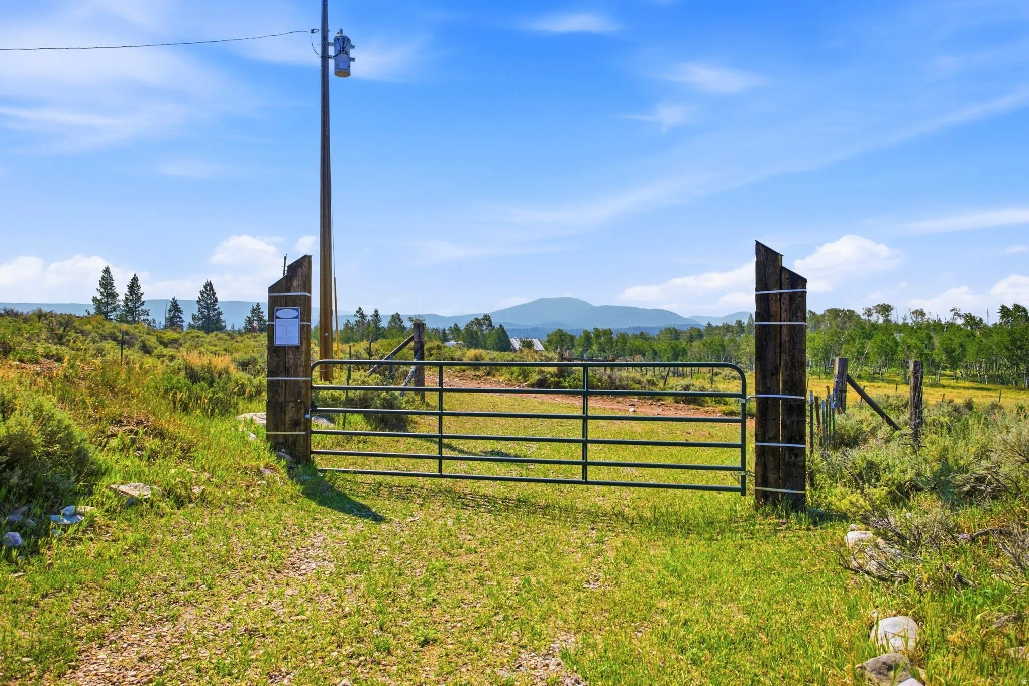 Gated entry to a property featuring a natural landscape with mature trees and distant mountain ranges