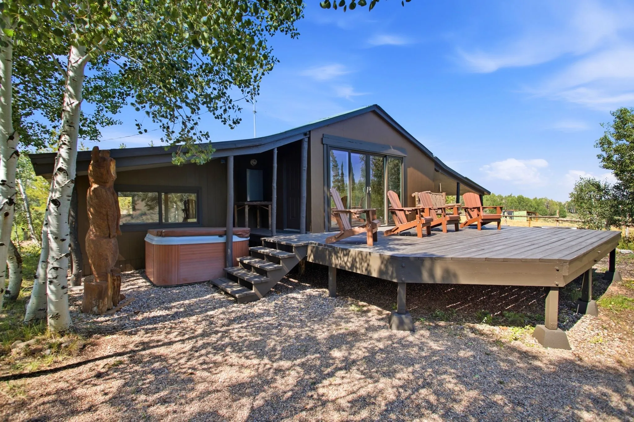 Expansive outdoor deck with integrated steps, large windows, and a built-in hot tub