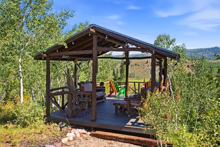 Wood-frame gazebo with a composite deck, surrounded by mature trees, offering an elevated position