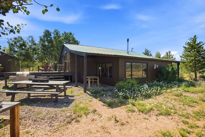 Wood-sided residence featuring a covered porch, metal roof, and multiple large windows